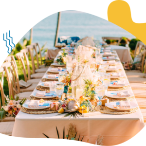 Elegant outdoor dining setup with floral decorations by the sea.