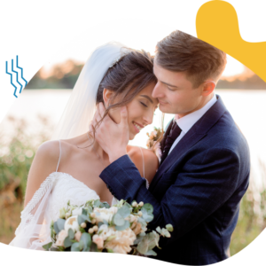 A groom tenderly kisses his bride's hand during their outdoor wedding.