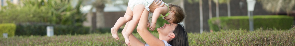 Parent lifting baby joyfully in the air, both smiling.