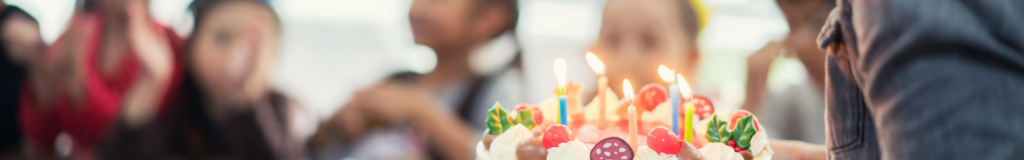 Close-up of a colorful birthday cake with a lit candle.