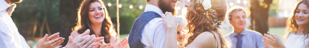 Woman's hand holding man's jacket over his shoulder outdoors.