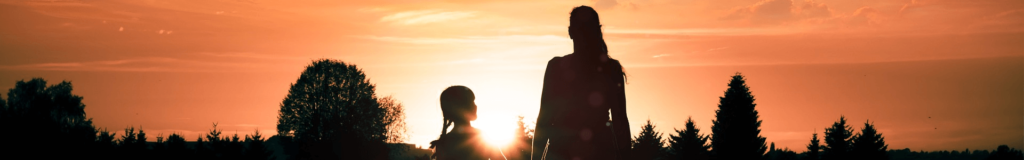 Silhouettes of two people holding hands at sunset.